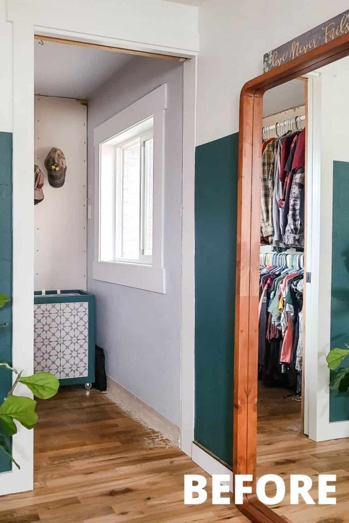 The entrance to a small walk-in closet with unfinished floor baseboards and walls. A large floor-length mirror leans against the wall outside the closet.