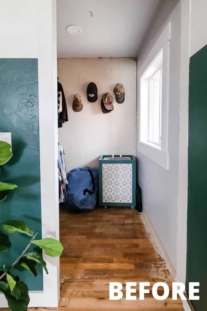 A look inside the master bedroom walk-in closer. Hats hang on hooks attached to plain unfinished drywall boards hung next to a window.