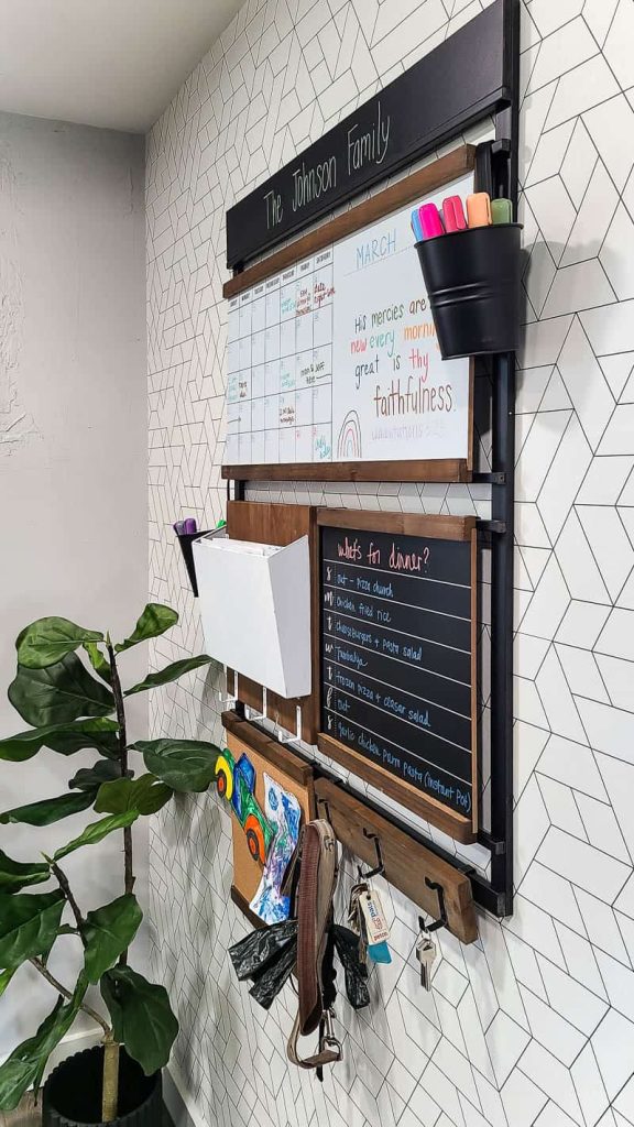 A side angle view of the customizable family command center that hangs on the wall, including a whiteboard. memo board, key hangers, and other convenient command center elements.