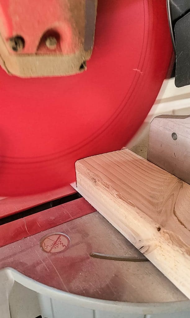 Cut wood 2x4s with a miter saw as instructed in DIY woodworking plans for dress up rack