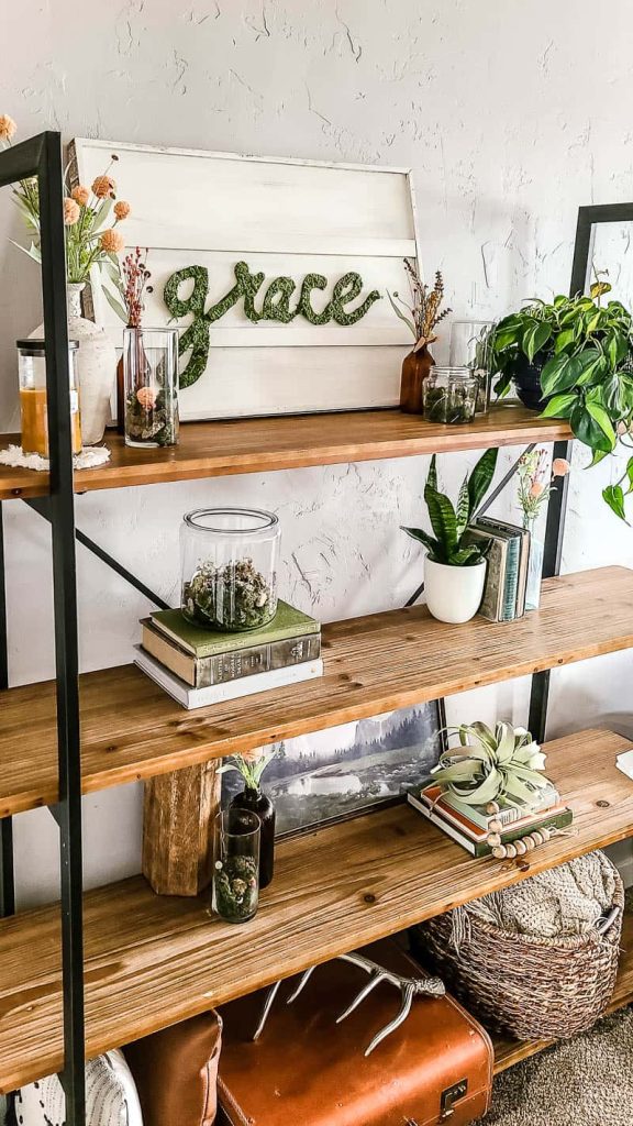 Industrial style shelves decorated for Spring with faux greenery, vases of florals, rocks, and moss, books, and DIY Spring inspired artwork.