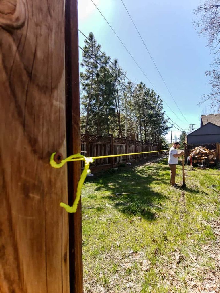 shows a guy lining up post and digging a post hole