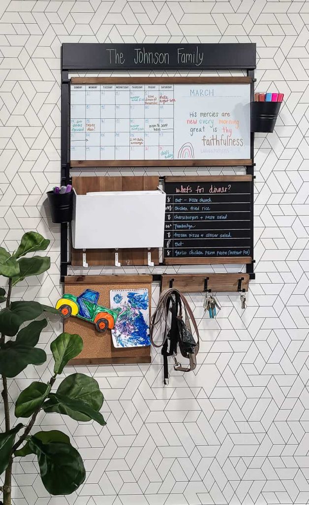 A straight-on image of the functional family command center hanging on the wall. This family command center includes a whiteboard calendar, memo board, mail holder, and key hooks.