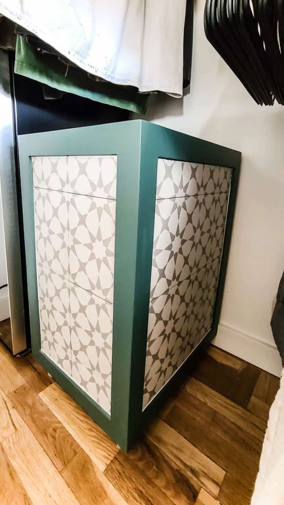 Wooden hamper with patterned tiled edges and green trim in the master closet