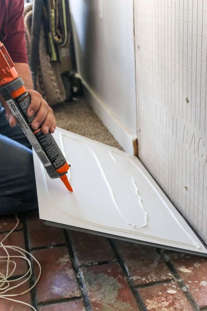 applying construction adhesive to the back of wall panels