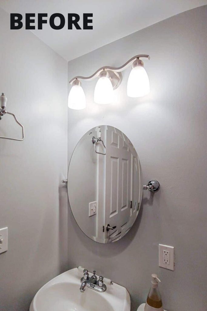 Oval wall mounted mirror, bathroom sink, soap, light fixture before the spray paint mirror update 
