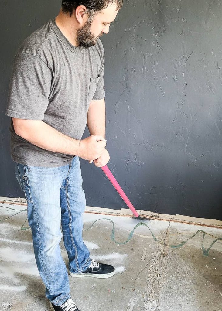 hombre usando raspador de piso para quitar la tira de tachuelas