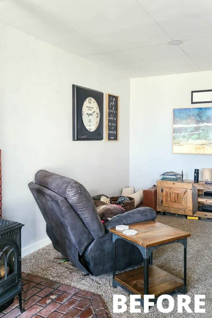 A corner of the large living room features a black leather recliner and wooden side table, positioned towards a gallery wall and entertainment center.