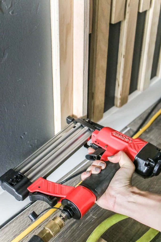 Woman nailing the wood slat in the wall using brad nailer