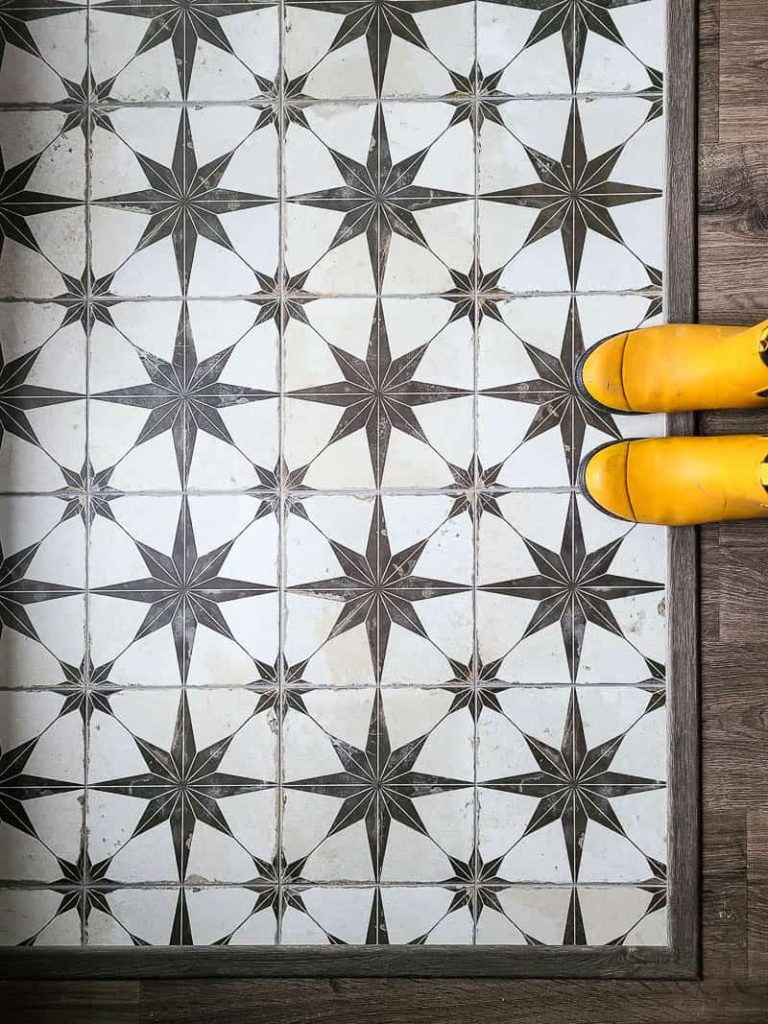 Ivory and brown star pattern Floor tiles laid on the floor in entryway with yellow boots on the side