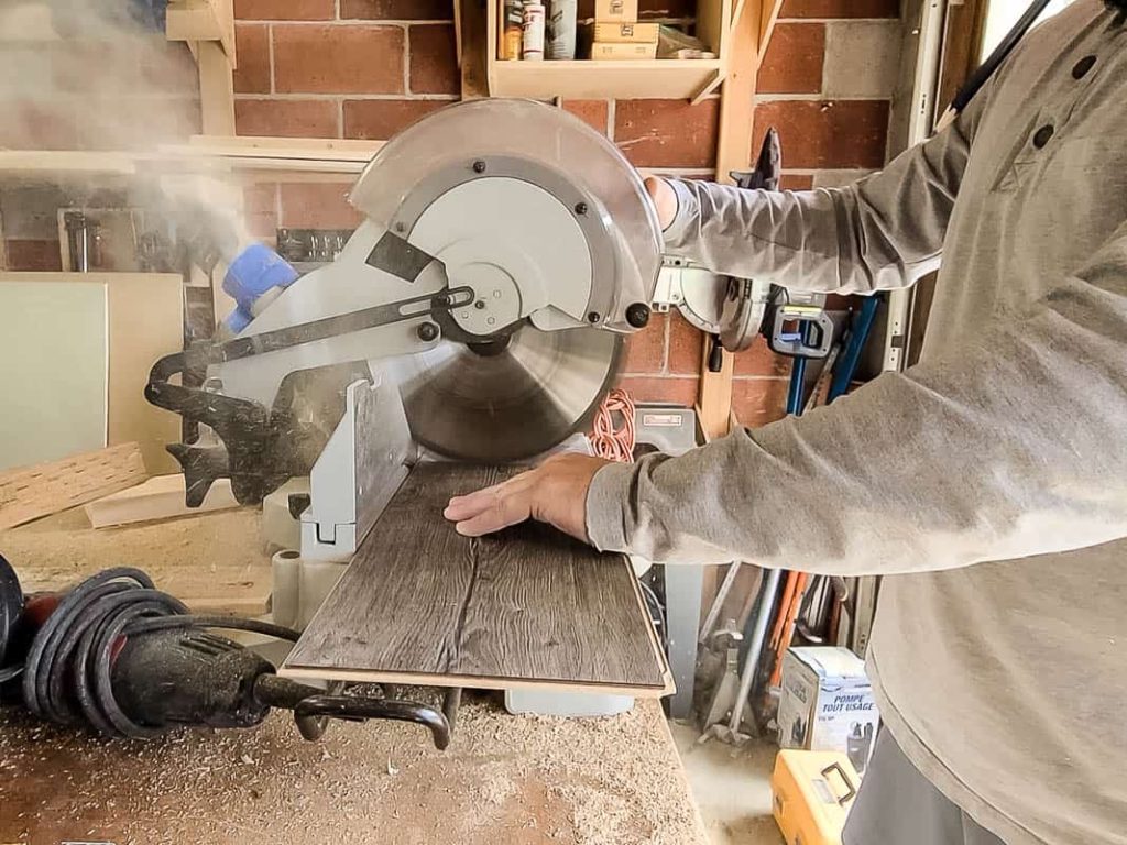 Man cutting the laminate using a miter saw on the table workbench