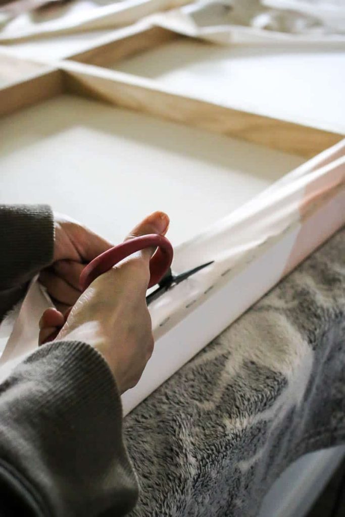Woman cutting the excess tapestry on the back of canvas using scissors