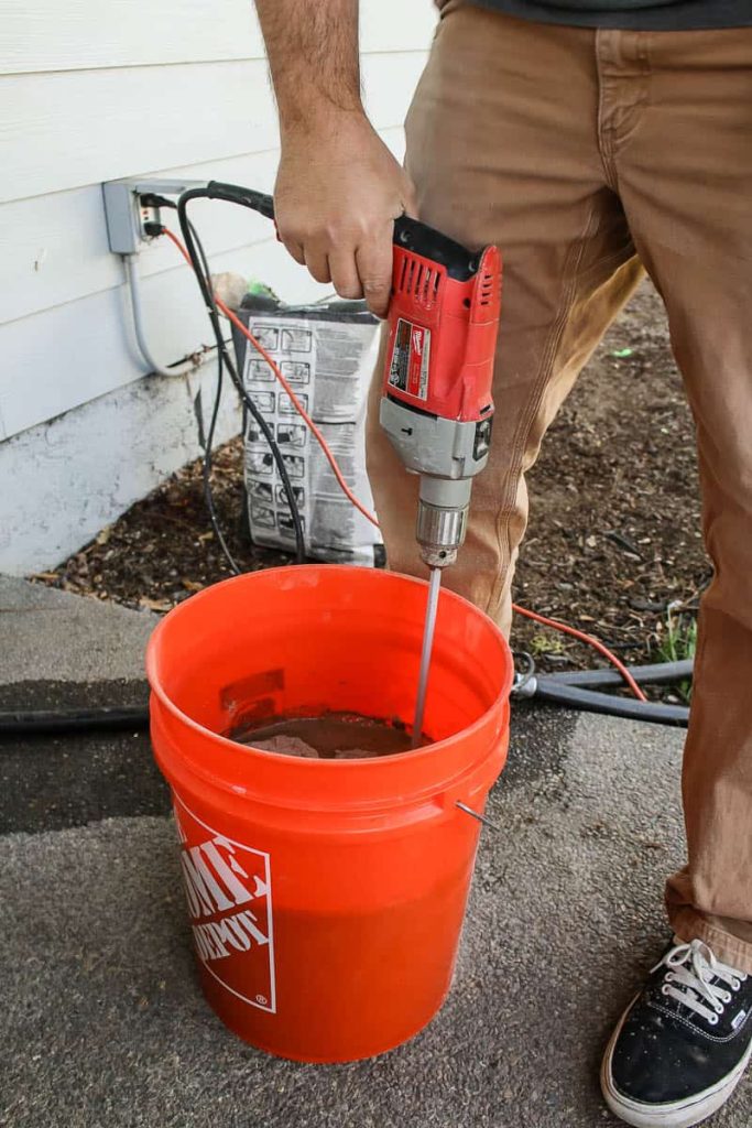 Man mixing tile mortar in the orange bucket