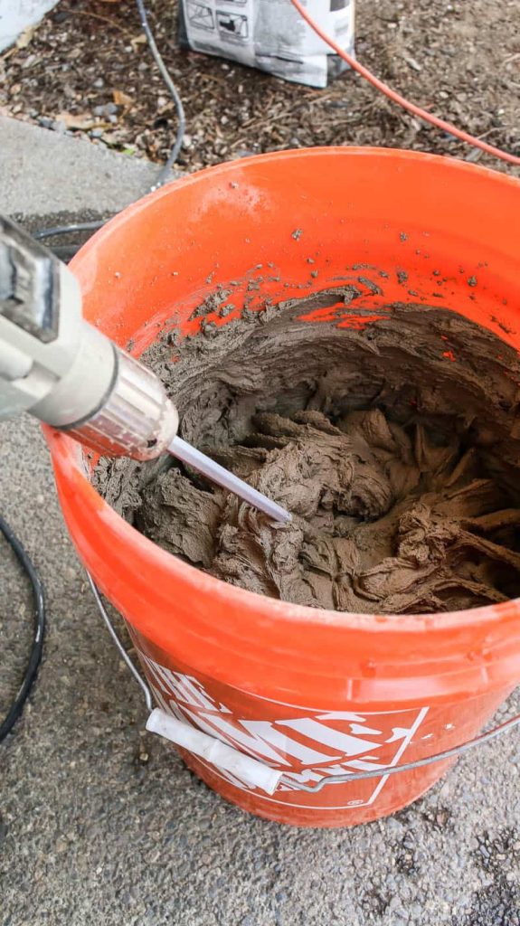 Drill mixing the thinset mixture inside the orange bucket