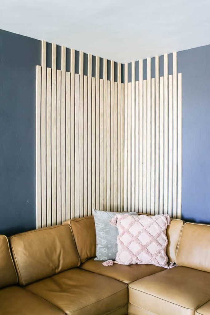 Wood slats as accent wall in the living room with dark gray walls with the leather couch and boho throw pillows