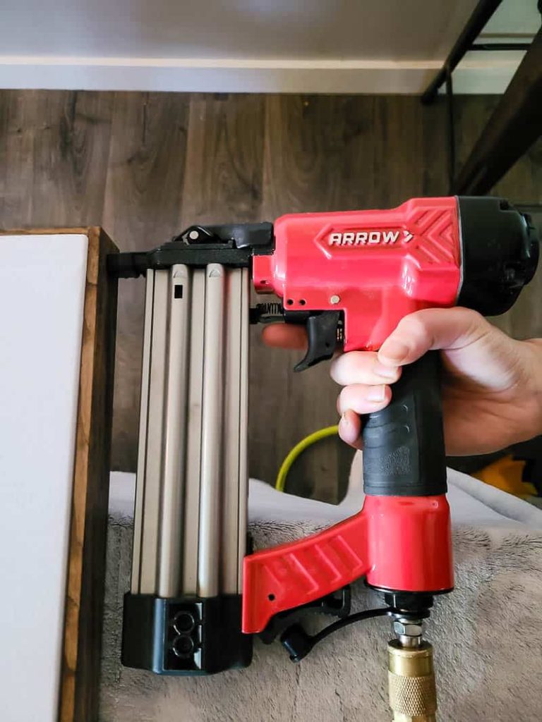 Nailing wood strips to the edge of the DIY tapestry frame using nail gun