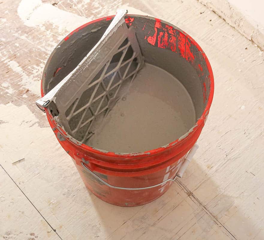 5 gallon of paint bucket with gray paint and grate inside