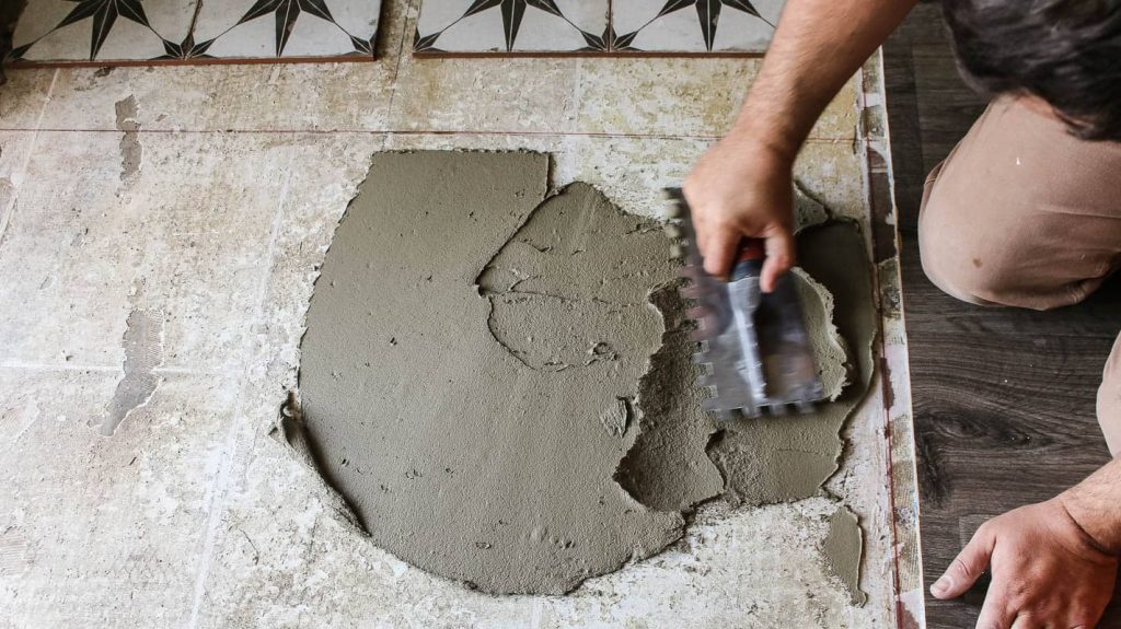 Man applying mortar on the floor with notched trowel