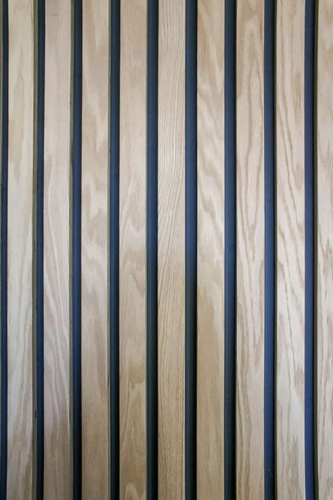 Close up of vertical wood boards on the wall with dark gray paint behind
