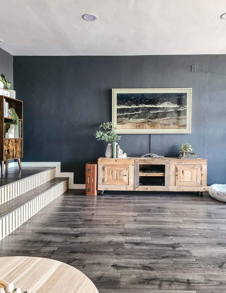 View from the sectional of TV console on wall opposite seating area in modern boho living room with dark gray wall a Samsung Frame TV hanging above.