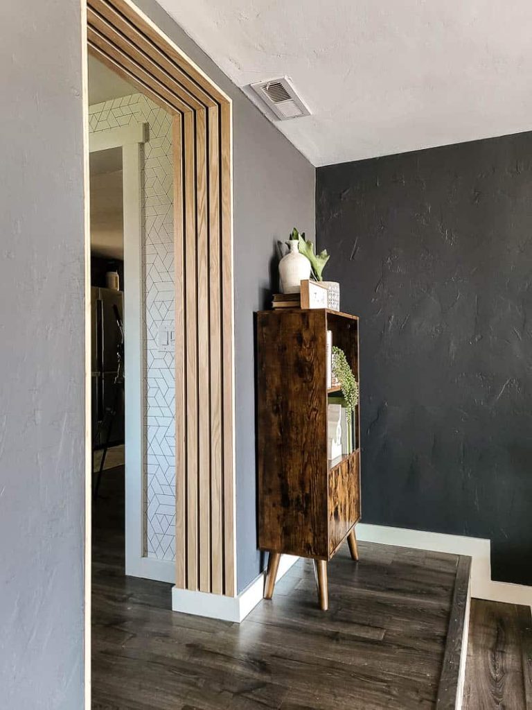Side view of mid century modern bookcase styled with books and greenery in modern boho living room corner on the extended stair platform.