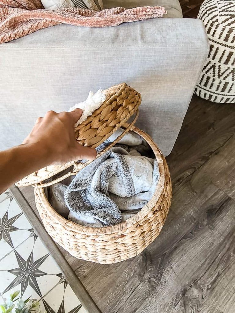 Inside of rattan basket with lid storing a blanket in a modern boho living room.