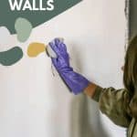 Woman wearing gloves wiping the wall with a cloth