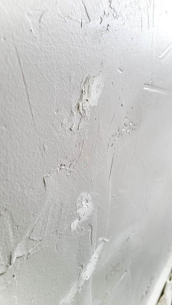 Side view of the white wall with spackle covering the nail hole