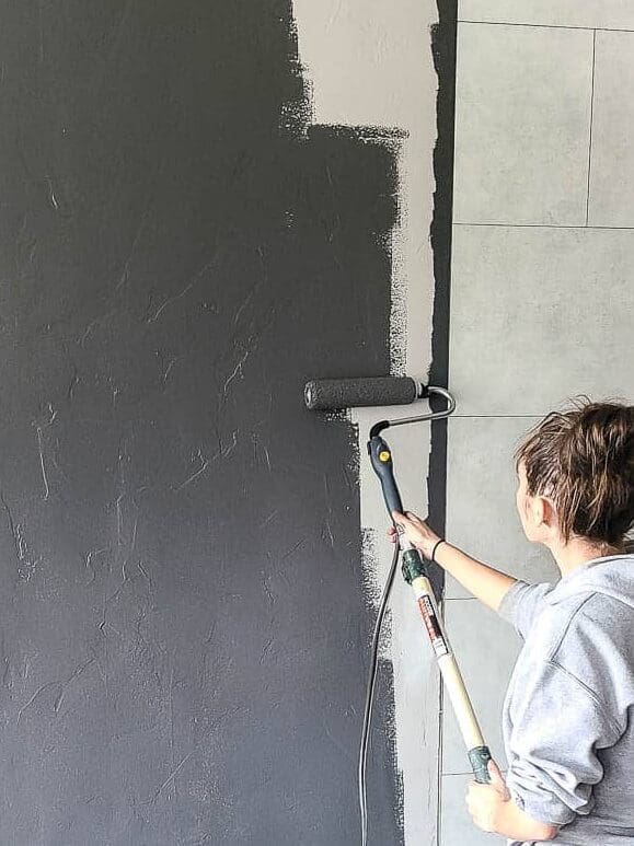 Rolling dark gray color onto walls of living room. There's a lot to consider when choosing paint colors for your home interior. Learn more about how to choose paint colors for your home interior in this guide