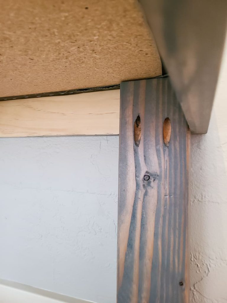 Close up of a board of the DIY bench with pocket holes and gel stain.