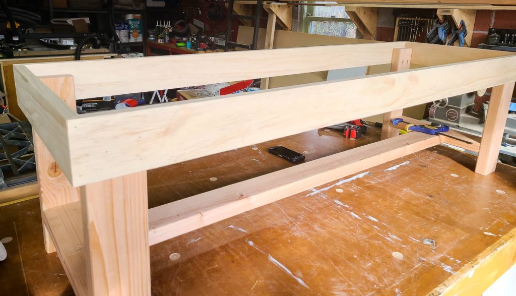 Frame of DIY bench with competed trim sitting on workbench.