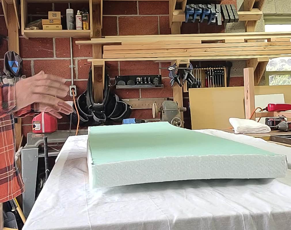Foam cushion laying on top of particle board before upholstering.