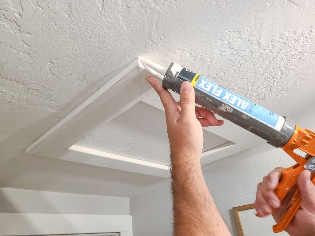 Caulk the edges of the framing where it meets the ceiling with DAP's Alex Flex caulk to give the scuttle hole a professional finish and remove any gaps or imperfections. 