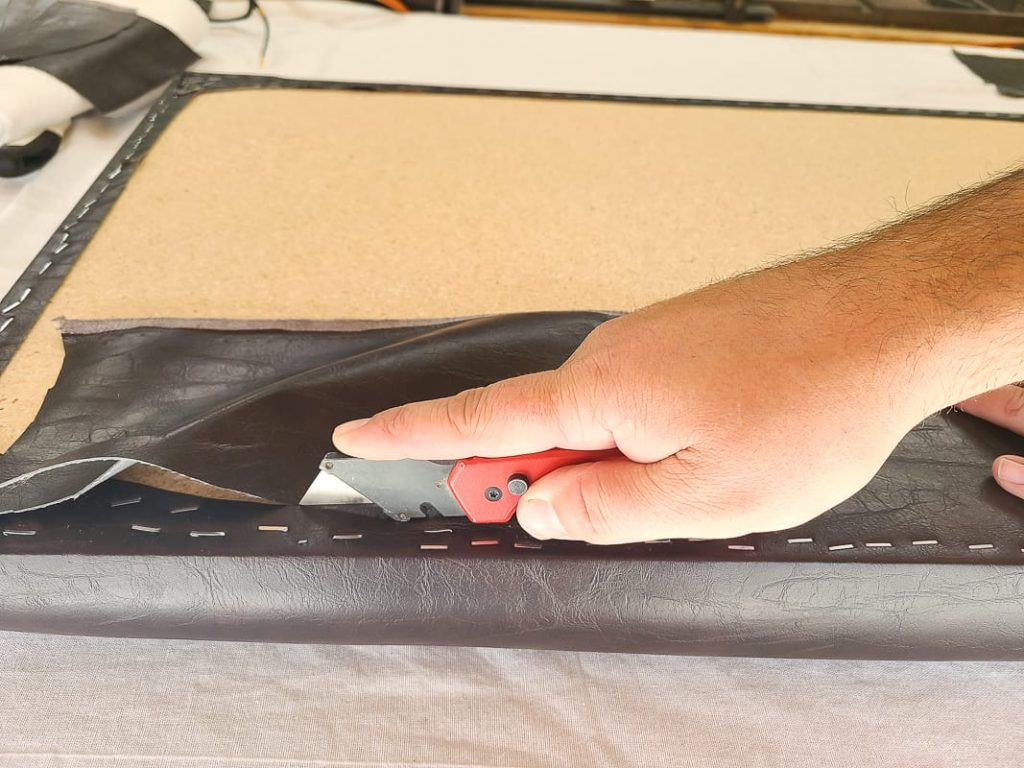 Cutting off excess leather material using a box knife.