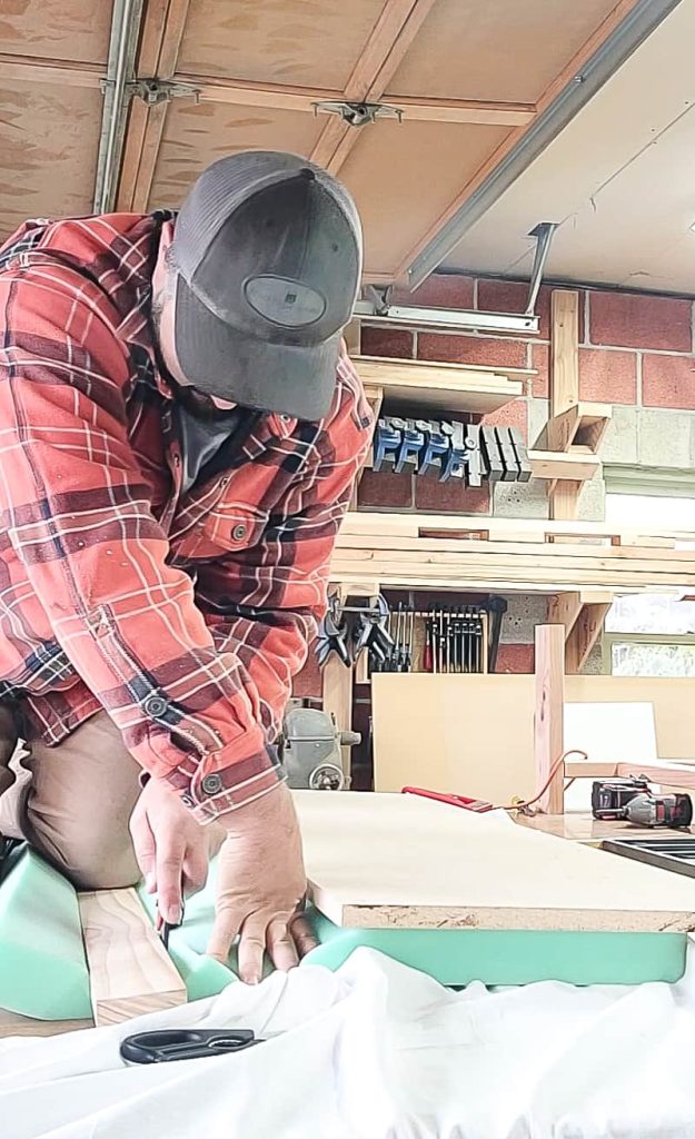 Man cutting foam cushion to size for DIY bench cushion.