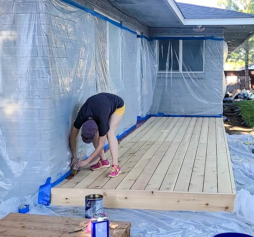 Woman sealing the house walls with plastic sheets and tape