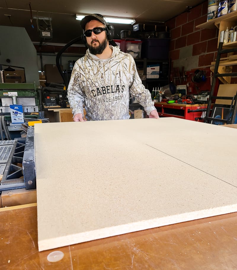 Man cutting particle board using a table saw.
