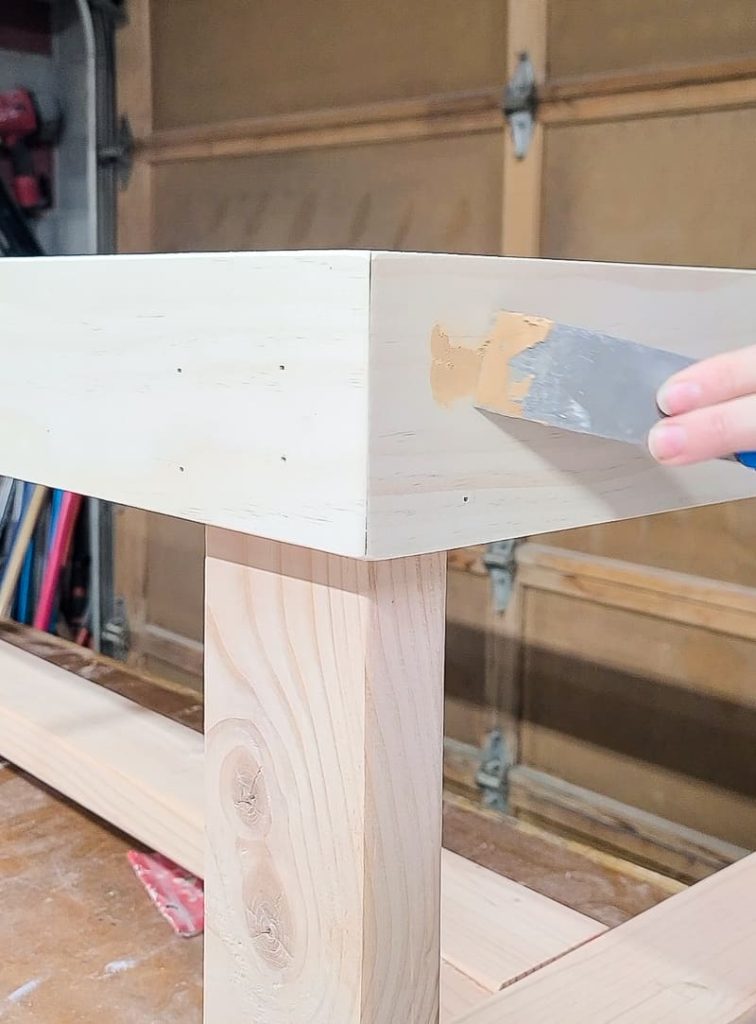 Filling nail holes with wood putty.