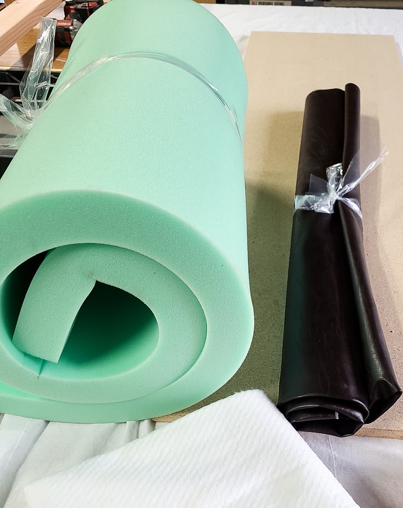 Rolled foam cushion and brown leather material to be used on DIY bench cushion.
