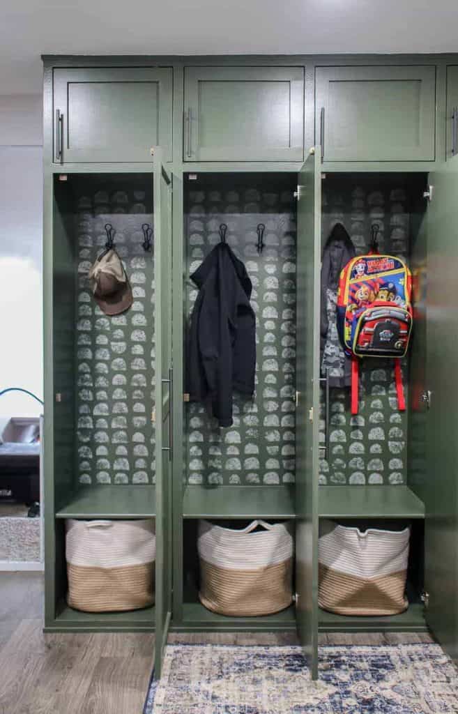 storage lockers painted in Behr Black Bamboo with a stenciled design inside cabinet and hooks with jackets and backpacks on the inside of the lockers