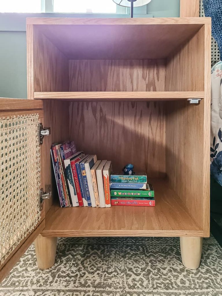 Close up of the DIY cane nightstand with opened doors showing books inside made with beside table plans