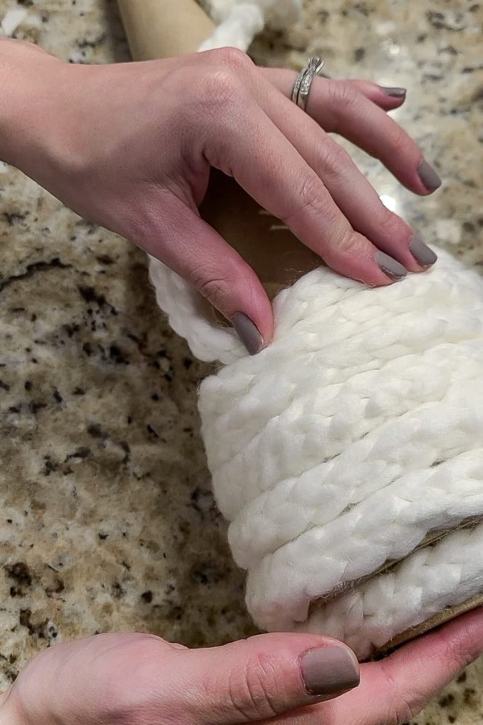 Pressing the white chunky yarn to the cardboard cone to secure attachment