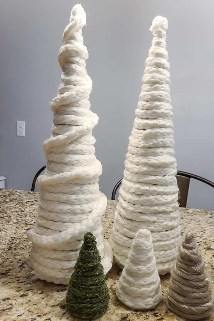 Small and big cardboard cone trees covered in different colored chunky yarns turned into DIY Yarn Christmas Trees