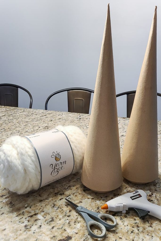 white yarn, two cardboard cone trees and scissors on the countertop