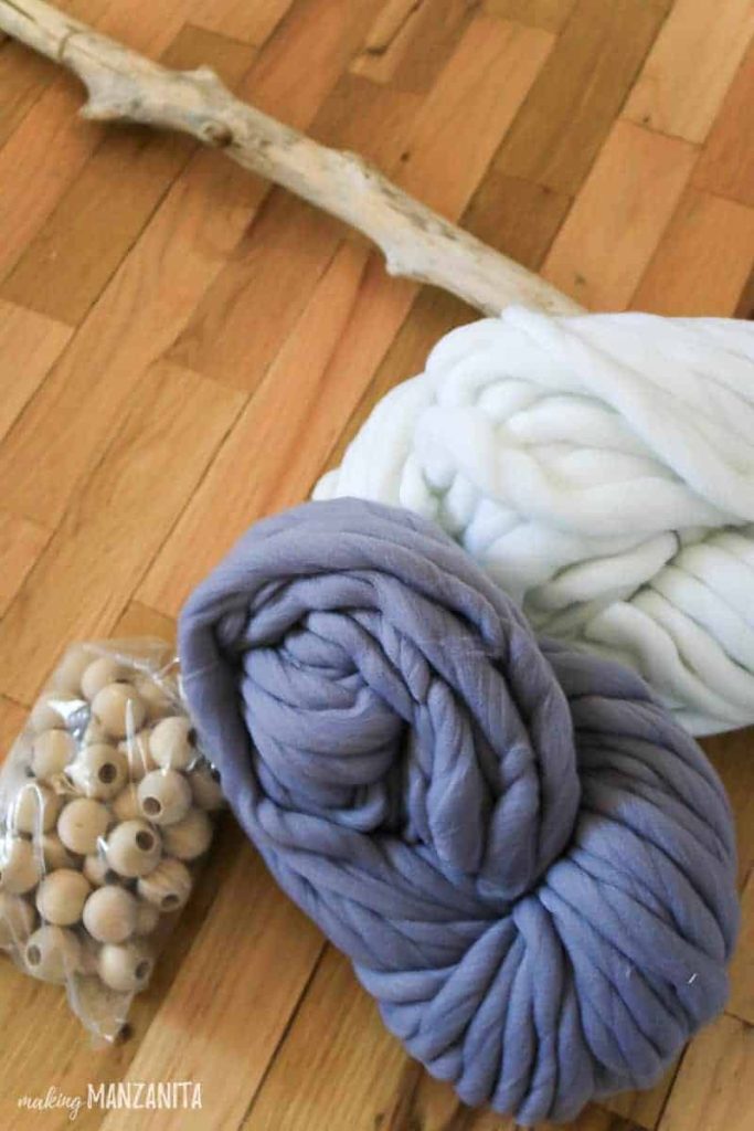 Supplies needed to make a boho yarn wall hanging: wooden beads and two colors of thick woven yarn - I used white and blue.