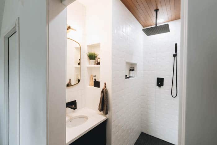 Modern black and white bathroom with walk in shower, black fixtures and tiled shower niche.