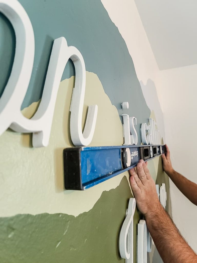 Getting the wooden letters up on the wall was the easiest part! Have one person hold the level in place and the other push the letters on the wall with picture hanging strips.