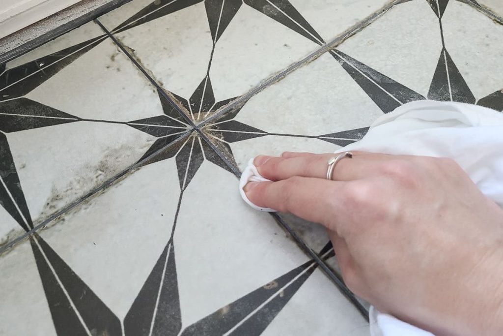wiping away grout sealant with a white rag