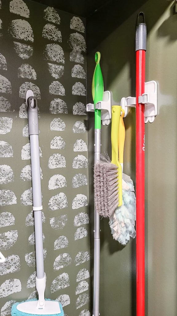 Image of cleaning accessories mounted on a wall with Command strips, providing a space-saving and convenient storage solution