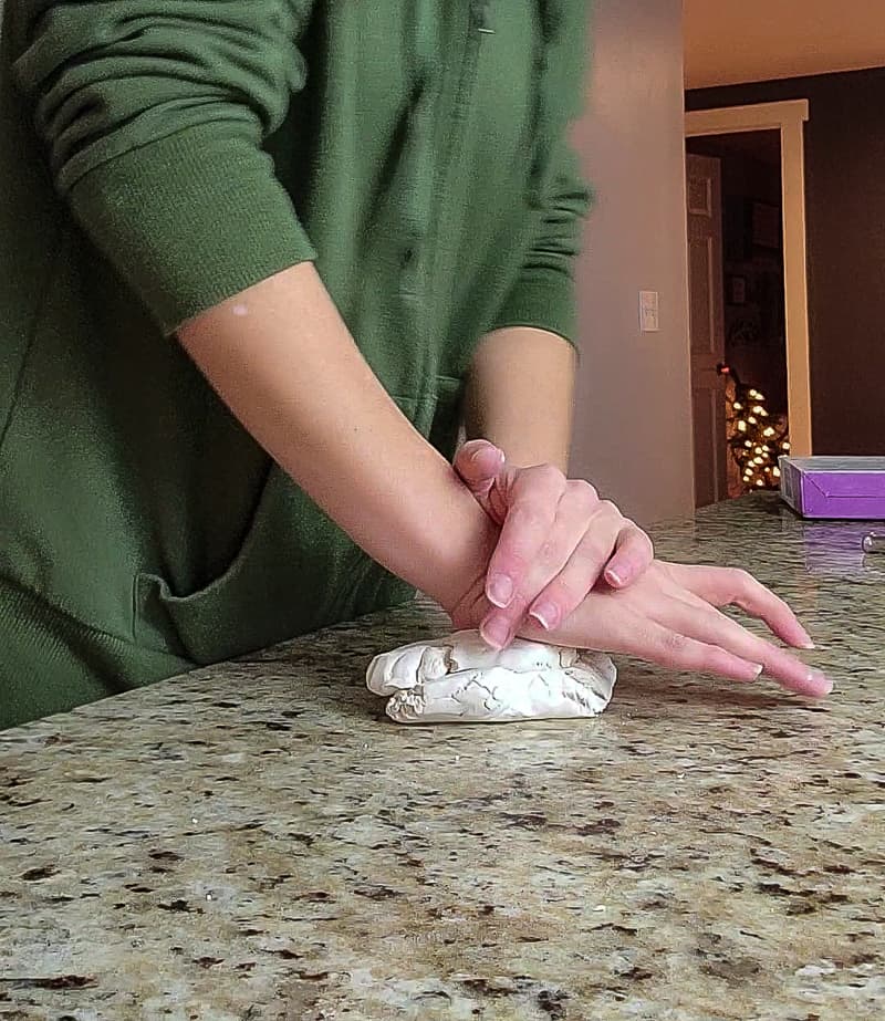 Chelsea kneading polymer clay on the kitchen counter before forming into a clay knot.